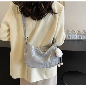 Detail of grey marble texture crescent bag with plush ball charm on a model's shoulder