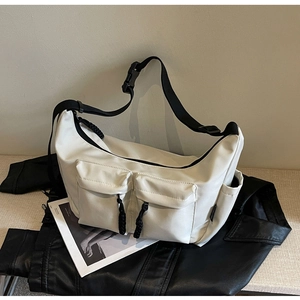 Detail view of cream canvas tote bag showing tactical pockets and buckle strap