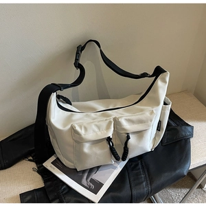 Detail of off-white canvas crossbody bag featuring functional pockets and black straps