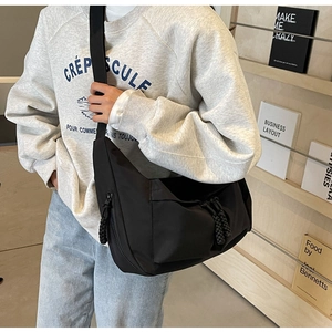Side view of black nylon crossbody tote bag with wide strap and rope zipper detail