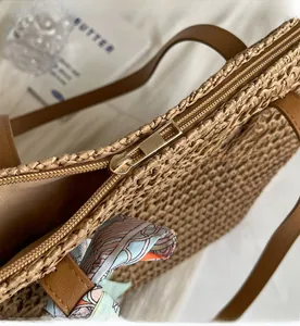 Detail view of smooth metal zipper and premium woven texture on the khaki straw tote bag