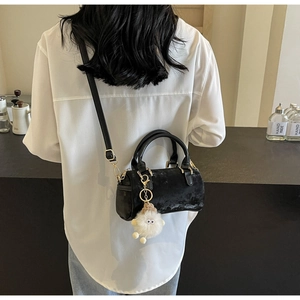 Detail view of black velvet Boston bag with plush doll charm and gold chain strap hooks