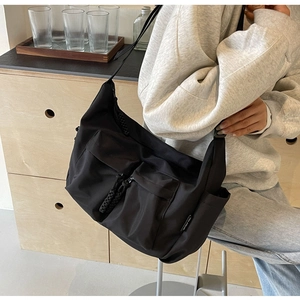 Detail of a black large-capacity crossbody bag showing functional pockets and nylon texture