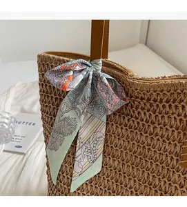 Detail of a woven straw tote bag featuring a decorative tropical floral print silk scarf