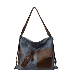 Large blue canvas tote bag with brown leather trim and multi-pocket functional design
