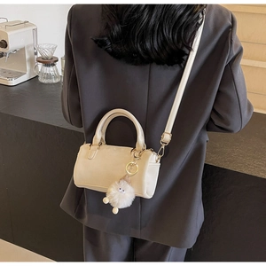 Creamy white Boston style crossbody bag detail featuring a cute plush doll pendant accessory