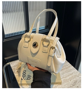 Detail of cream Boston bag featuring pleated sides and gold-tone metal hardware