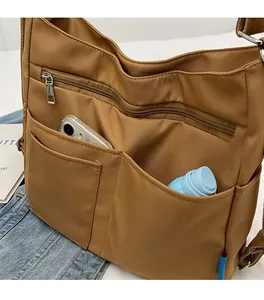 Detail of brown multi-pocket tote bag showing spacious storage for phone and bottle