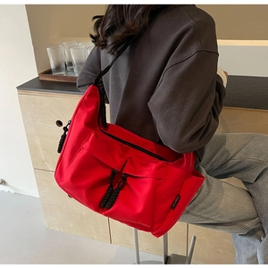 Detail of red nylon tote bag featuring cargo pockets and black woven rope puller accents