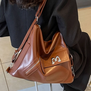 Braune Hobo-Tasche aus Leder mit silbernem M-Logo und breitem Gurt an der Modelausschulter