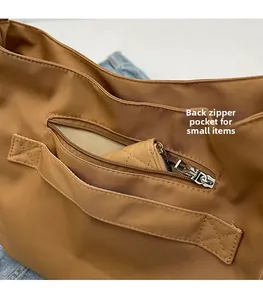 Detail of the back zipper pocket on a brown messenger bag storing a small wallet