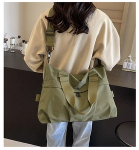 Close-up of military green nylon tote bag with adjustable strap worn by a model
