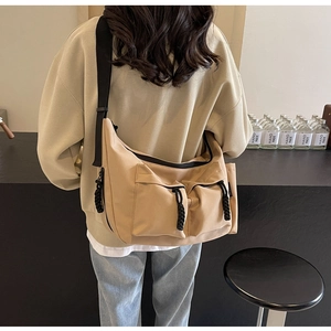 Detail of beige canvas tote bag showing front flap pockets and adjustable black strap