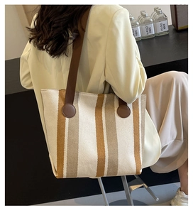Detailed back view of a large striped canvas tote bag with brown fabric shoulder straps