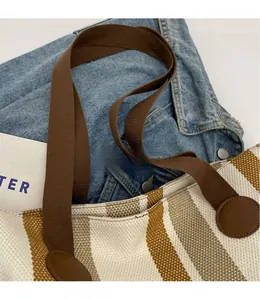 Close-up of durable shoulder strap with leather patch on a striped canvas tote bag