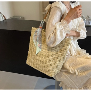 Detail of woven straw tote bag with decorative silk scarf and textured craftsmanship