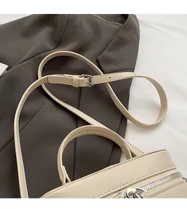 Détail du sac seau beige montrant la bandoulière réglable et la boucle argentée