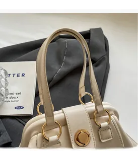 Close-up of cream Boston bag featuring gold metal rings and retro leather texture detail