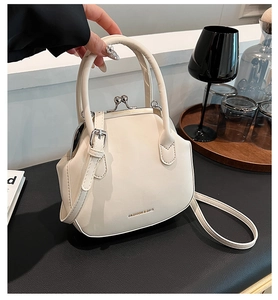 Close-up of cream PU leather doctor bag with silver kiss-lock and hand-held strap