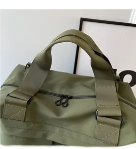 Close-up of army green nylon tote bag featuring reinforced handles and dual metal zippers