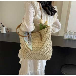 Straw tote bag detail with leather handles and decorative silk scarf for summer
