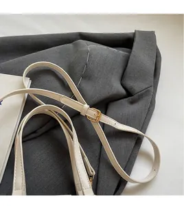 Detail of adjustable leather shoulder strap with gold metal buckle on white Boston bag