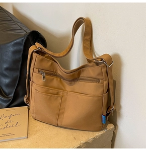 Detail of a brown multi-pocket nylon shoulder bag with adjustable strap and casual style