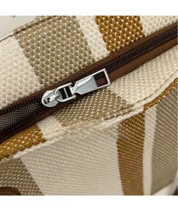 Detailed macro view of the silver metal zipper pull on a striped woven tote bag