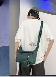 Detail of dark green nylon messenger bag with mini pouch and adjustable strap on model