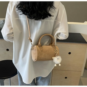 Detail of khaki Boston handbag with plush sheep charm worn over a white shirt