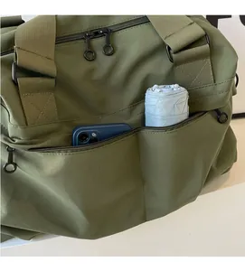 Detail of army green nylon tote featuring a functional side zipper pocket with a phone