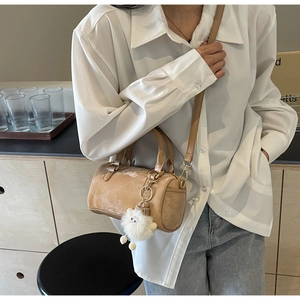 Detail of camel cylindrical boston bag with cute white plush lamb pendant and shoulder strap