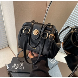 Close-up of black Boston bag with vintage metal clasp and adjustable shoulder strap
