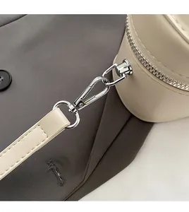 Détail d'un sac en cuir beige avec un crochet métallique argenté amovible et coutures soignées