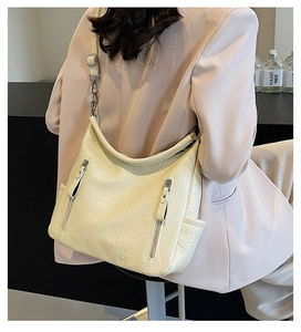 Gros plan du sac cabas en cuir grainé crème avec fermetures éclair et poches latérales