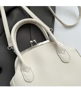 Detail of white leather doctor bag featuring a metal ball clasp and padded handle
