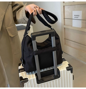 Detail of the back luggage strap on a black large capacity nylon tote travel bag