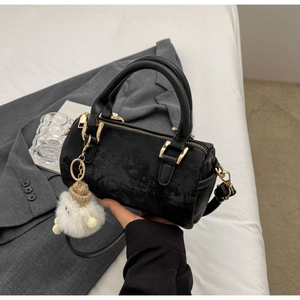 Detail of black Boston bag with gold hardware and a cute plush doll keychain charm