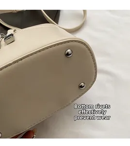 Détail des clous de protection en argent sous le mini sac crème contre l'usure précoce