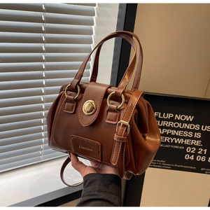 Close-up of caramel retro doctor bag with gold hardware lock and pleated texture
