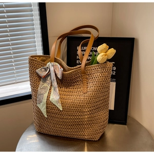 Detailed weave pattern of a summer straw tote bag with brown leather handles and scarf