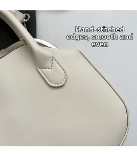 Detailed close-up of premium hand-stitched leather handle on a cream white handbag