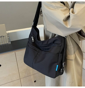 Detail view of multi-pocket black nylon crossbody bag with adjustable wide shoulder strap