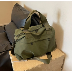 Olive green nylon tote bag on stone base showing the adjustable shoulder strap and texture
