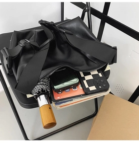 Detail view of large black tote bag showing interior space with a wide shoulder strap