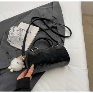 Close-up of black velvet Boston bag with gold hardware and a cute plush monster charm