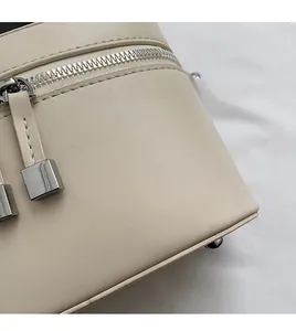 Détail de la fermeture éclair argentée et texture cuir synthétique crème d'un sac seau chic