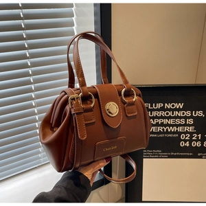 Detail of a brown Boston bag with a gold lock and Chan'2ab brand plaque on leather