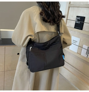 Close-up of black nylon shoulder bag with multiple zippers and adjustable metal buckle