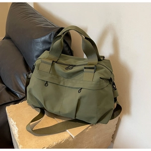 Army green nylon tote bag on stone pedestal with adjustable strap for commuting
